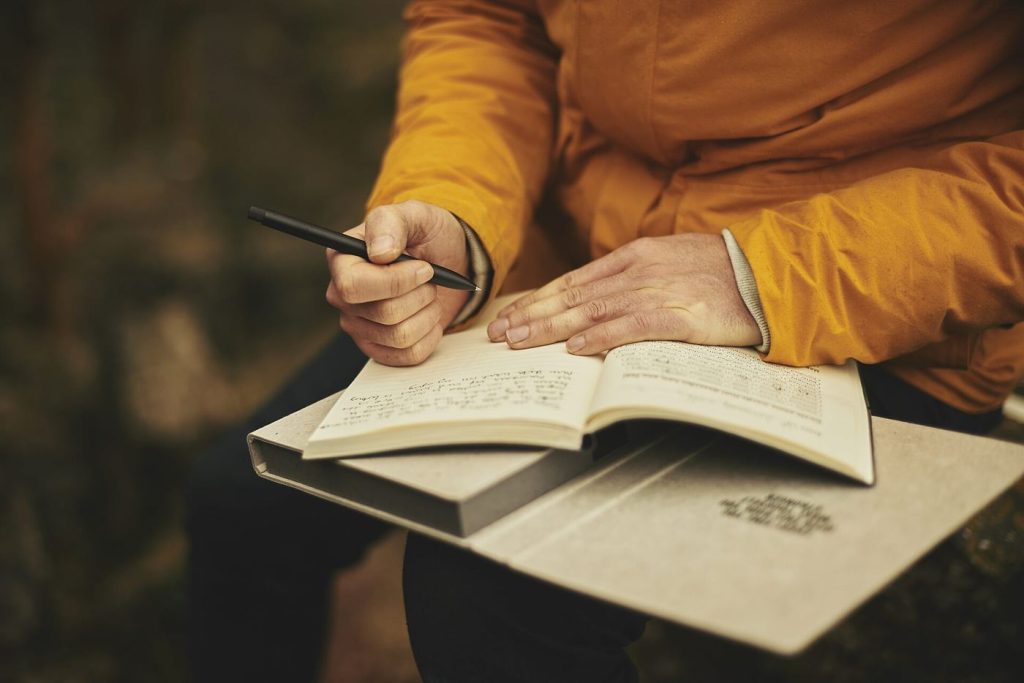 A person writing in a notebook at a tidy desk