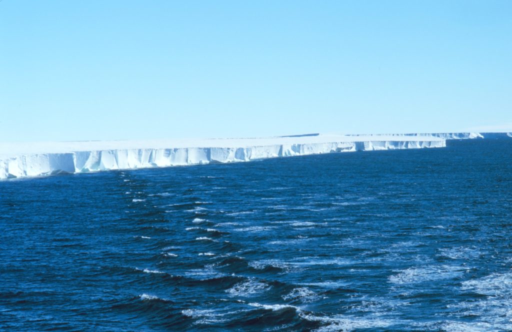 A vast Antarctic ice shelf meeting the ocean under a clear sky
