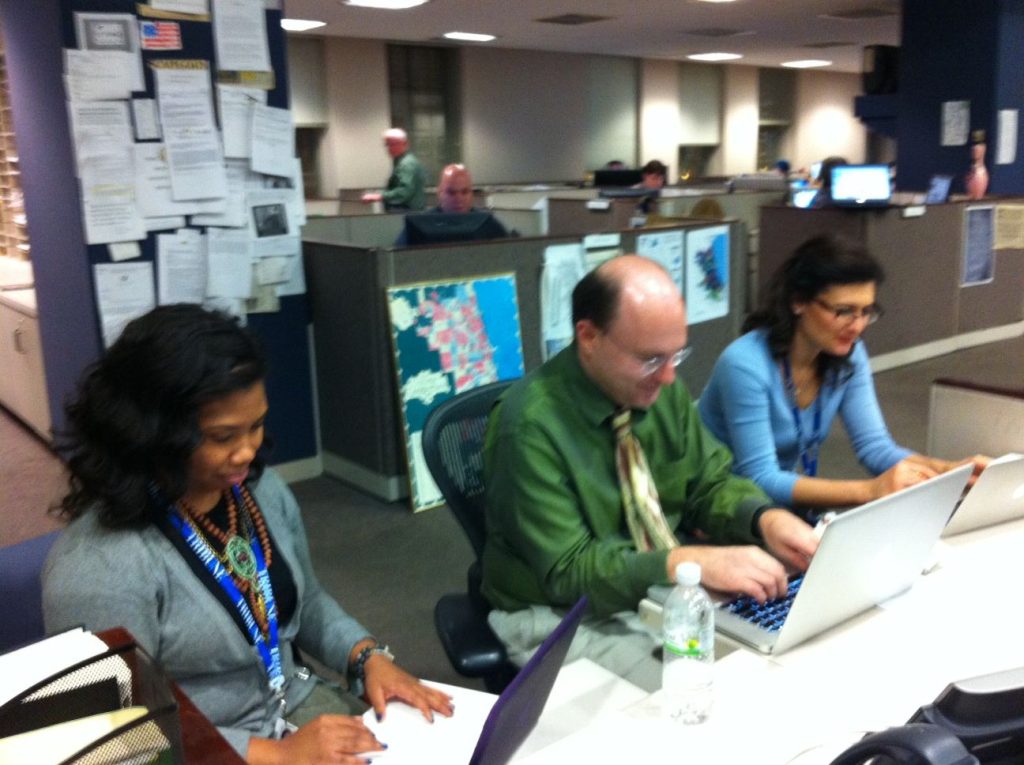 Journalists working at laptops inside a modern newsroom